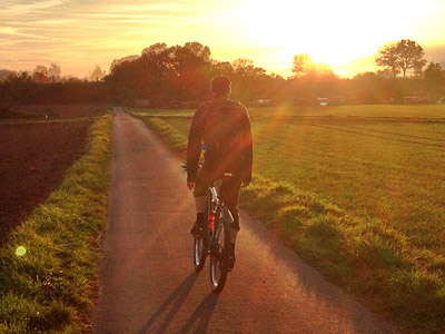 Ein Radfahrer fährt einen Weg entlang bei Sonnenuntergang.